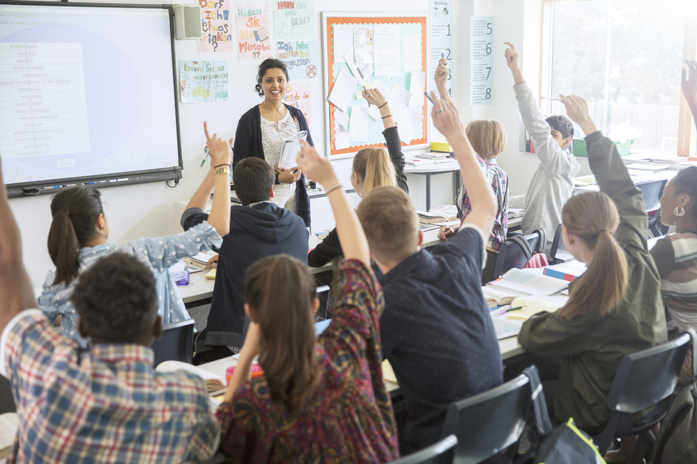 Unterrichtsstunde mit Schüler:innen die aufzeigen.
